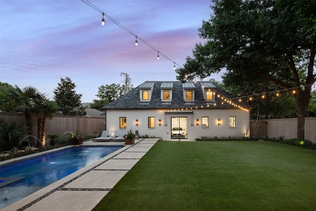 rear view of property with metal roof, a fenced backyard, a yard, a fenced in pool, and stucco siding