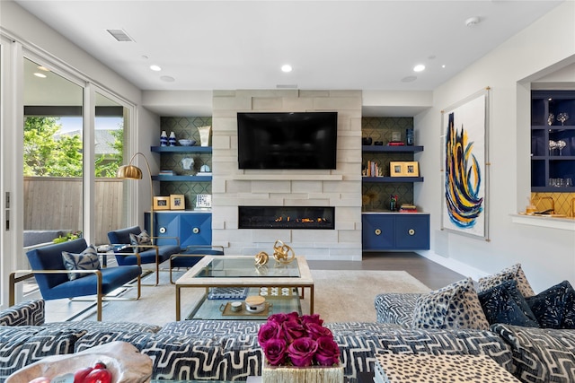 living room with recessed lighting, a large fireplace, wood finished floors, visible vents, and baseboards