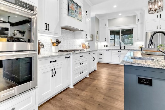 kitchen with white cabinetry, stainless steel appliances, a sink, and wood finished floors