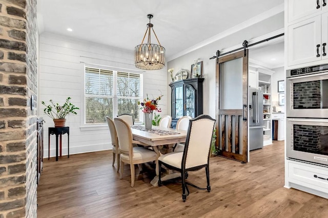 dining room featuring plenty of natural light, a barn door, and light wood finished floors