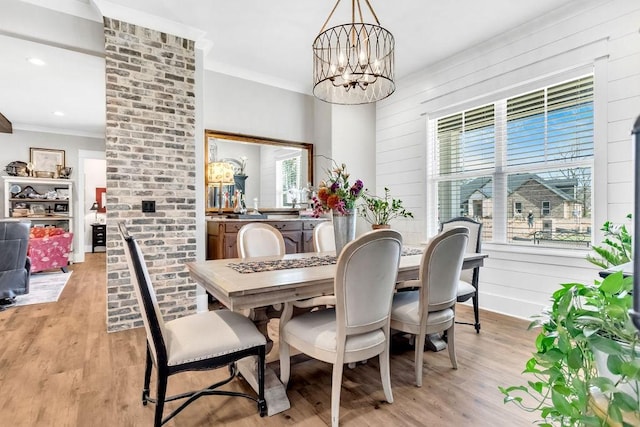 dining area featuring crown molding, wooden walls, light wood-style flooring, and a notable chandelier