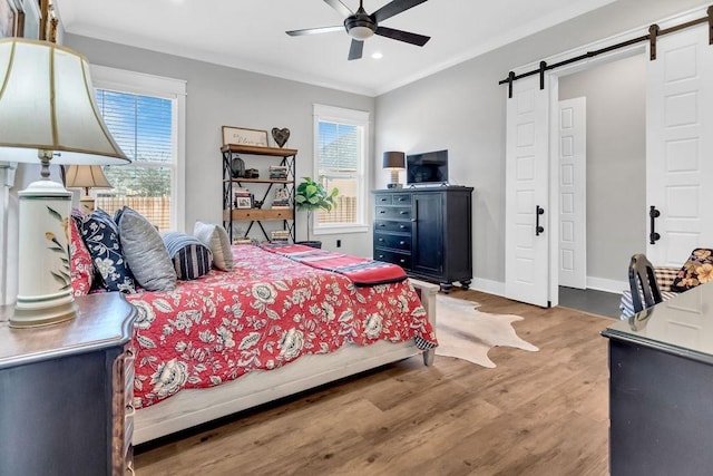 bedroom featuring a barn door, multiple windows, wood finished floors, and baseboards