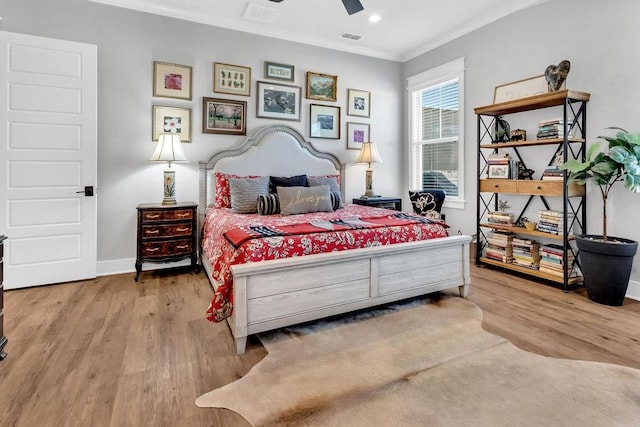 bedroom featuring ornamental molding, light wood-type flooring, visible vents, and baseboards