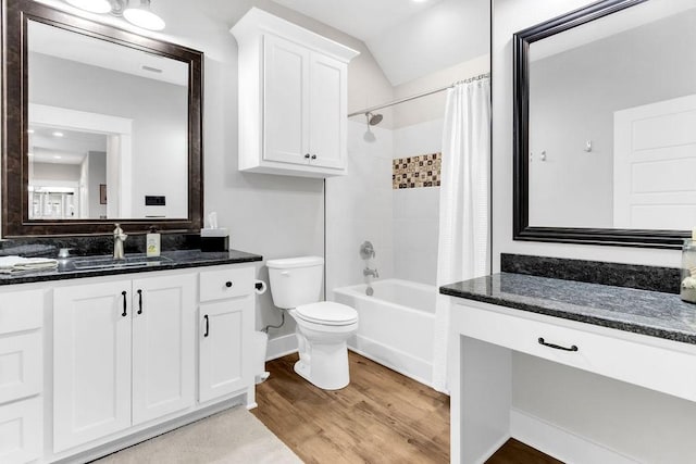 full bath featuring toilet, shower / tub combo with curtain, wood finished floors, vaulted ceiling, and vanity