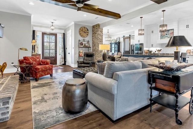 living area with dark wood-style floors, a barn door, ornamental molding, beamed ceiling, and baseboards