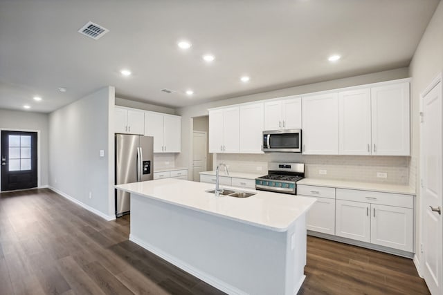 kitchen with a sink, white cabinets, appliances with stainless steel finishes, dark wood finished floors, and a center island with sink