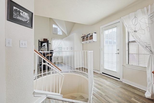 entrance foyer with a textured wall, baseboards, and wood finished floors