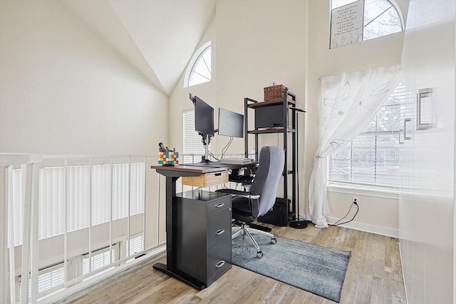 office space featuring light wood-type flooring and high vaulted ceiling