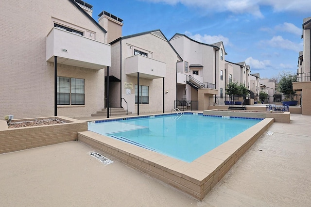 pool with a patio area, fence, and a residential view