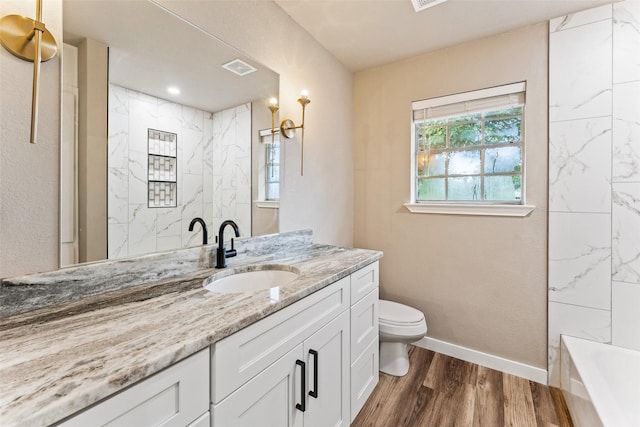 full bathroom with a bathtub, toilet, vanity, wood finished floors, and baseboards