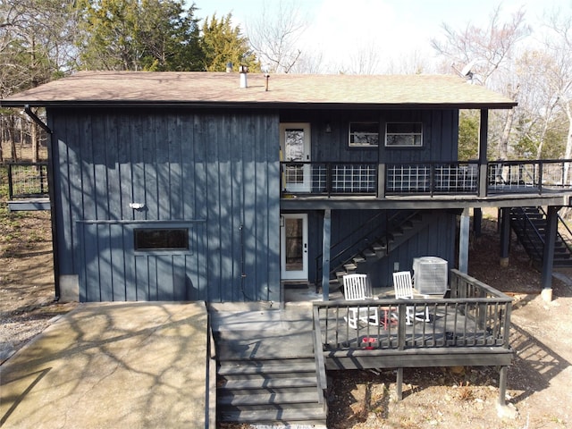 back of house with cooling unit, roof with shingles, a deck, and stairs