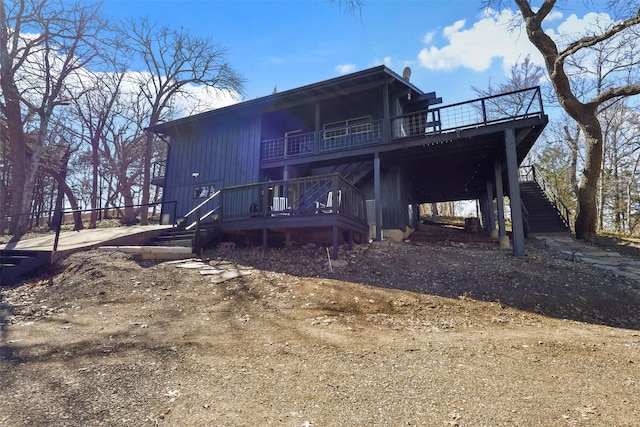 rear view of house with stairs, dirt driveway, and a deck