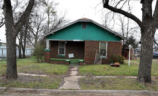 bungalow-style home with brick siding and fence