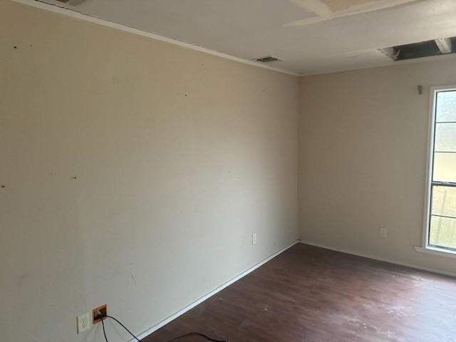 unfurnished room featuring wood finished floors, visible vents, and baseboards