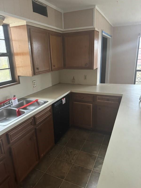 kitchen with black dishwasher, light countertops, a sink, and a wealth of natural light