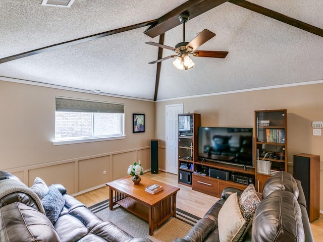 living room featuring lofted ceiling with beams, a wainscoted wall, ceiling fan, a textured ceiling, and light wood-style floors