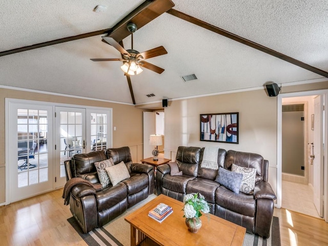 living room featuring visible vents, light wood-style flooring, lofted ceiling with beams, ceiling fan, and a textured ceiling