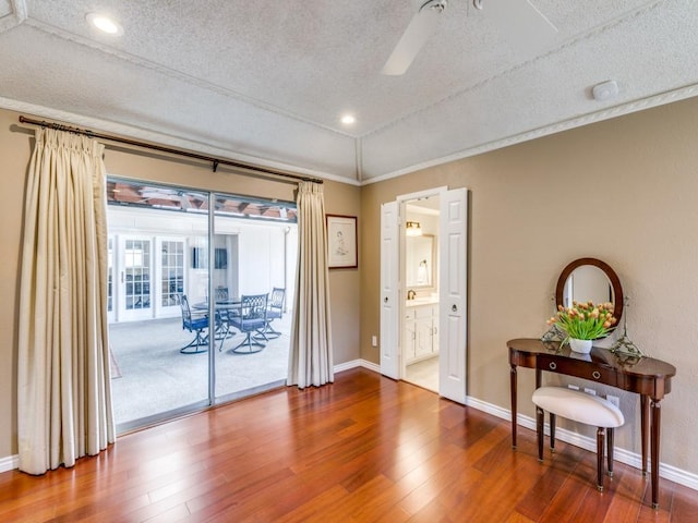 interior space with ceiling fan, a textured ceiling, baseboards, and wood finished floors