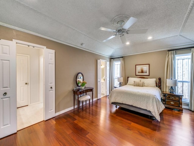 bedroom with crown molding, lofted ceiling, hardwood / wood-style floors, a textured ceiling, and baseboards