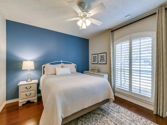 bedroom featuring a ceiling fan, a textured ceiling, baseboards, and wood finished floors