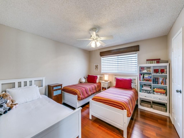 bedroom with a ceiling fan, a textured ceiling, and wood finished floors