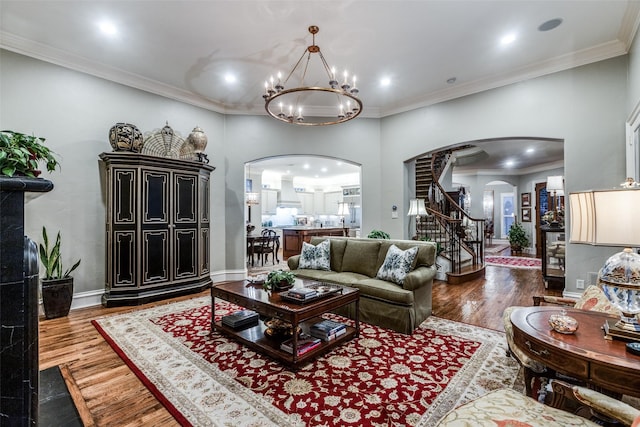 living area with ornamental molding, arched walkways, dark wood finished floors, and stairway