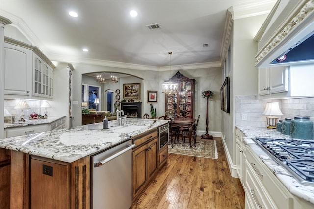 kitchen with visible vents, custom range hood, glass insert cabinets, stainless steel appliances, and a fireplace