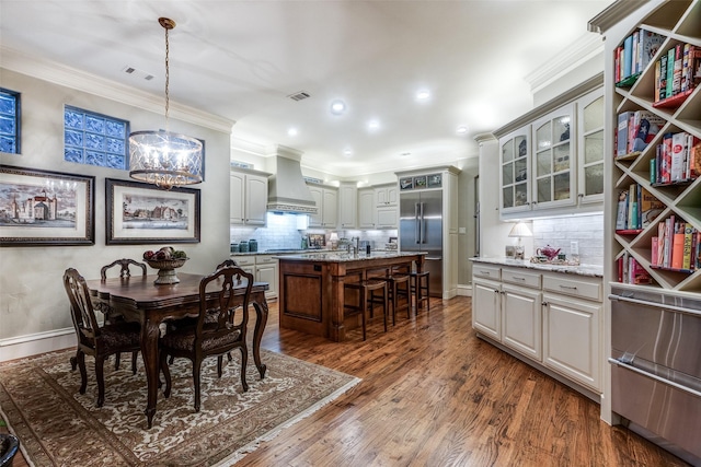 dining space featuring dark wood finished floors, visible vents, crown molding, and baseboards