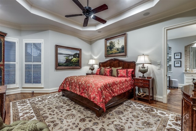 bedroom with a tray ceiling, wood finished floors, and crown molding