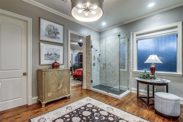 ensuite bathroom featuring ornamental molding, connected bathroom, a shower stall, and wood finished floors