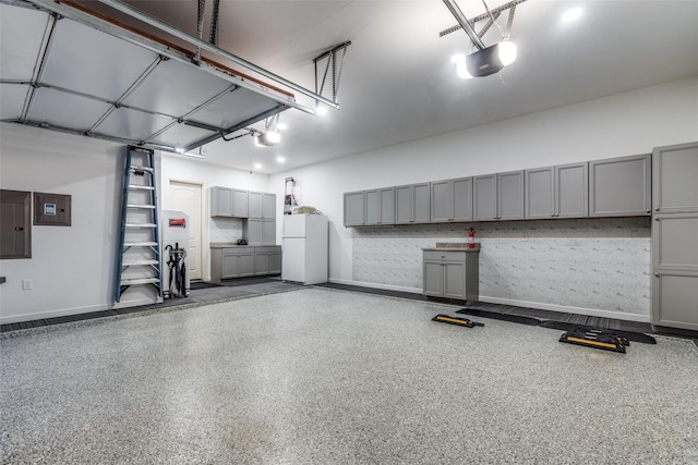 garage featuring baseboards, electric panel, freestanding refrigerator, and a garage door opener