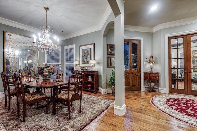 dining space with ornamental molding, arched walkways, french doors, and wood finished floors