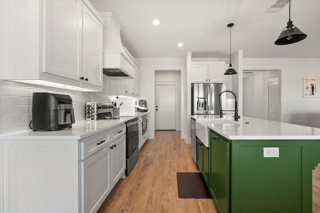 kitchen featuring tasteful backsplash, white cabinets, light wood-style flooring, appliances with stainless steel finishes, and green cabinets