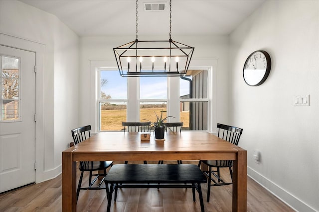 dining area with light wood-style flooring, visible vents, and baseboards