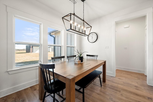 dining space featuring a notable chandelier, wood finished floors, and baseboards