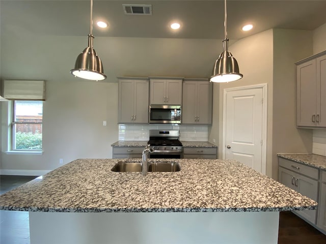 kitchen featuring visible vents, a sink, stainless steel appliances, gray cabinetry, and backsplash