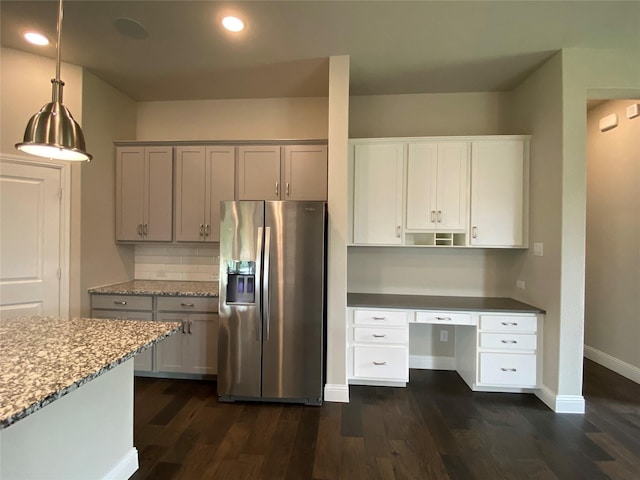 kitchen featuring decorative light fixtures, dark wood finished floors, built in study area, stainless steel fridge, and baseboards