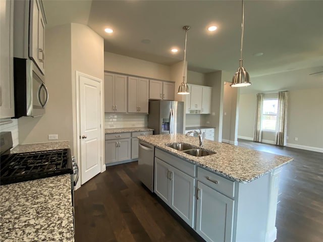 kitchen with dark wood finished floors, stainless steel appliances, gray cabinetry, decorative backsplash, and a sink