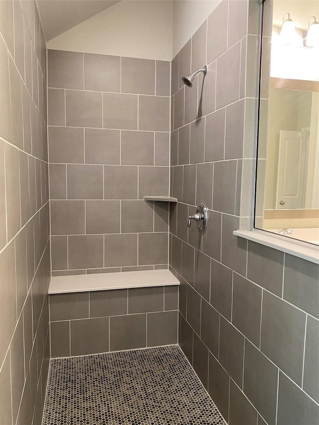 bathroom featuring vaulted ceiling and tiled shower