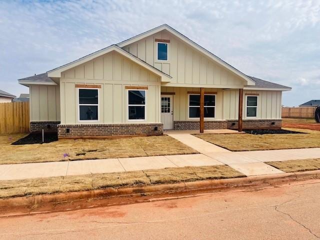 view of front of property featuring board and batten siding, brick siding, and fence