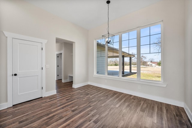 unfurnished dining area featuring an inviting chandelier, baseboards, and dark wood-type flooring