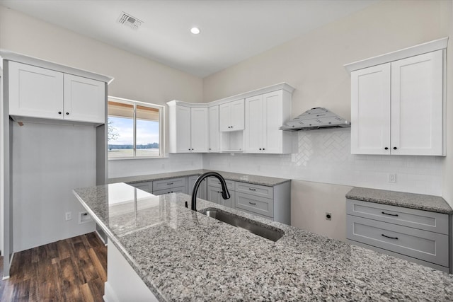 kitchen with tasteful backsplash, visible vents, light stone counters, and a sink