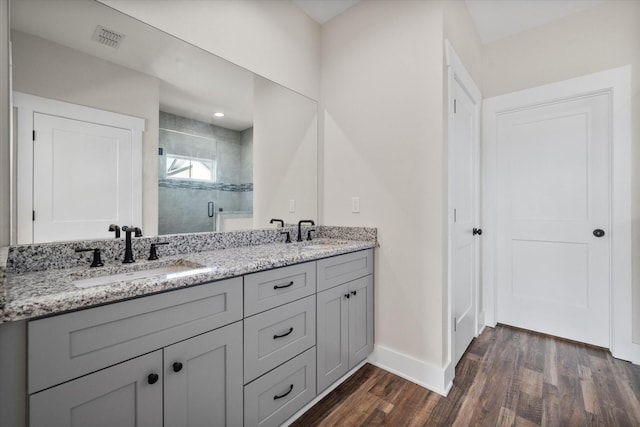 full bathroom featuring visible vents, a sink, a shower stall, and wood finished floors