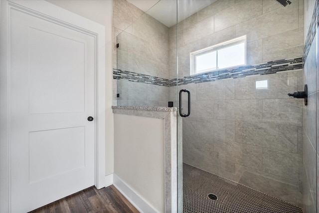 bathroom featuring a stall shower, wood finished floors, and baseboards