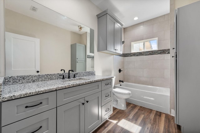 full bathroom with shower / bath combination, visible vents, toilet, vanity, and wood finished floors