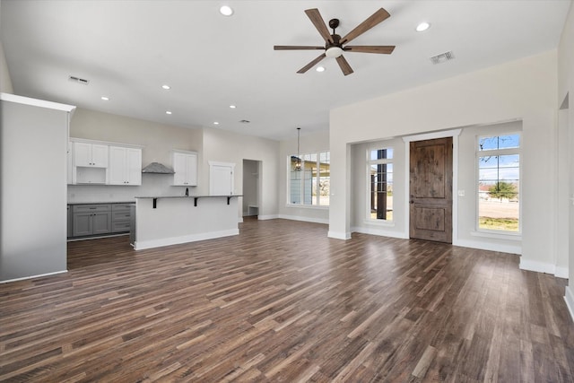 unfurnished living room with baseboards, visible vents, a ceiling fan, dark wood-style flooring, and recessed lighting