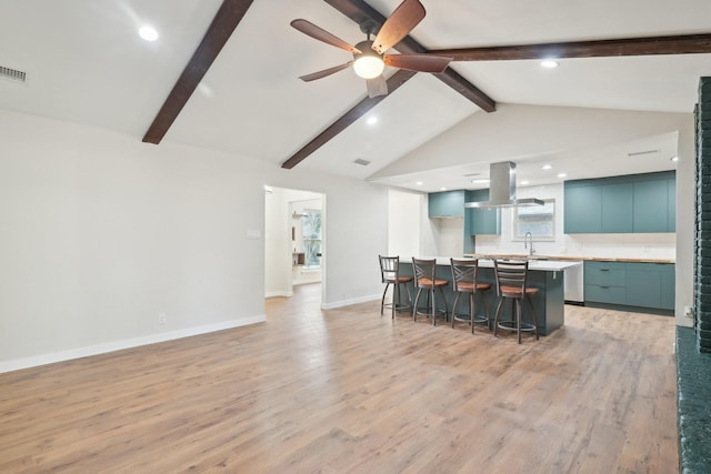 kitchen featuring a breakfast bar, vaulted ceiling with beams, island exhaust hood, light countertops, and light wood-type flooring