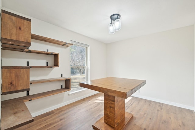 dining area with light wood-type flooring and baseboards