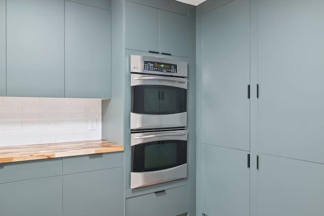 kitchen with tasteful backsplash, stainless steel double oven, butcher block counters, and gray cabinetry