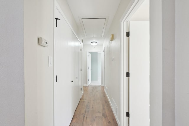 hallway with light wood-type flooring and attic access